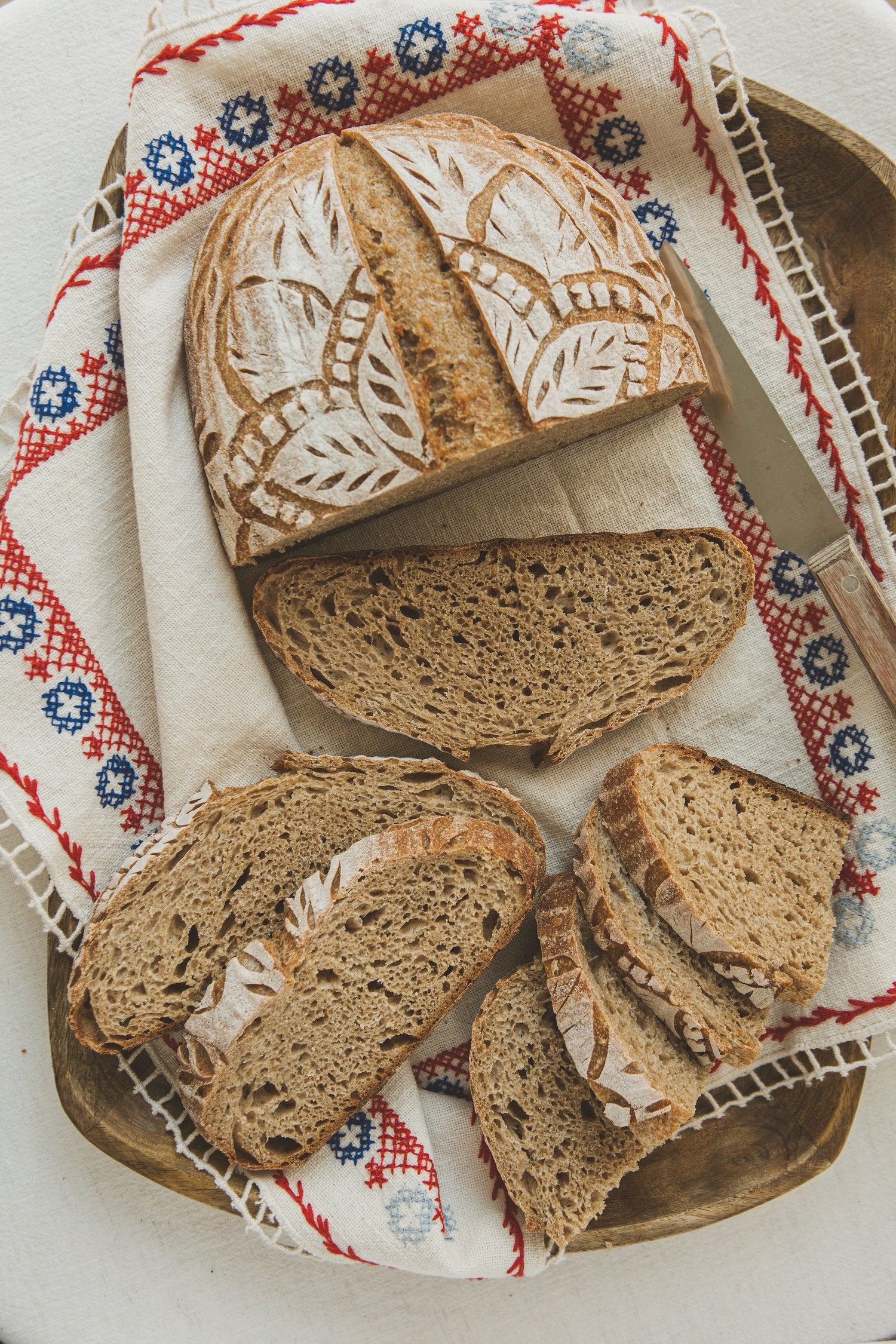Sliced loaf of bread on a decorative cloth with a knife